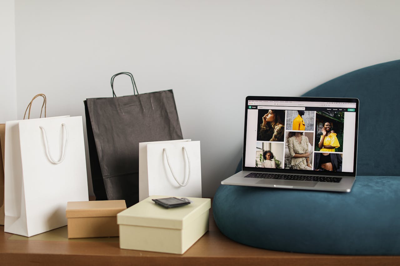Laptop showcasing fashion e-commerce site alongside shopping bags, ideal for online shopping themes.